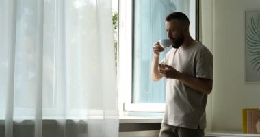 Uyum. Evdeki pencerenin yanında çay içen adam.