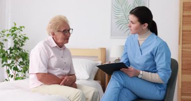 İçeride yaşlı bir kadını muayene eden bir hemşire. Ev sağlık hizmetleri