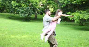 Aile kaçamağı. Mutlu ebeveynler parkta kızlarıyla eğleniyor.