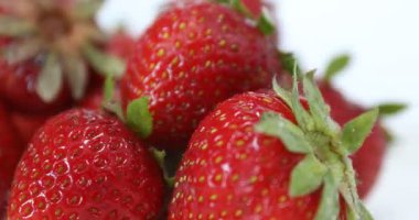 Beyaz arka planda bir sürü taze olgun çilek dönüyor.