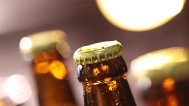 Bulanık arka planda damlaları olan bir şişe lezzetli bira, kamera aşağı iniyor.