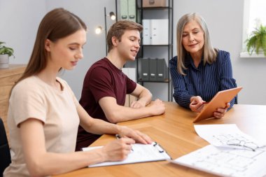 Tabletli emlakçı ofiste bir çiftle çalışıyor.