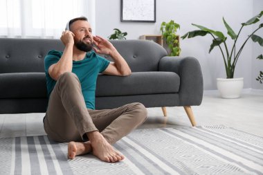 Uyum. Evde kulaklıkla müzik dinleyen bir adam.