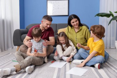 Ebeveynler çocuklarına evde yerde çizim yapmayı öğretiyor.