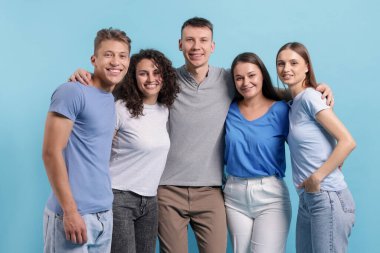 Açık mavi arka planda kucaklaşan arkadaş grubu