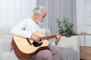 Rahatlatıcı hobi. Son sınıf öğrencisi evdeki kanepede gitar çalıyor.