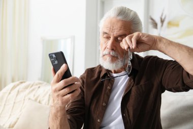 Evdeki kanepede akıllı telefon kullanan görme sorunu olan son sınıf öğrencisi.