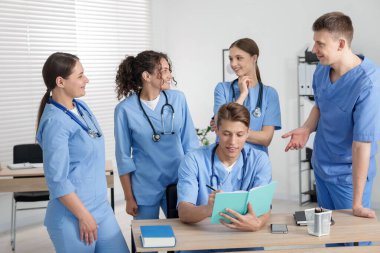 Üniversitede üniformalı tıp öğrencileri birlikte okuyorlar.