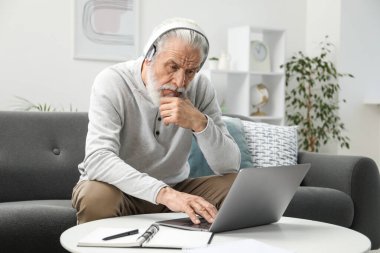 Üst düzey bir adam internette bilgisayarla kapalı bir masada öğreniyor. Kendi kendine çalışma.