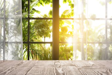 Odasında perdeler olan pencereye karşı boş ahşap masa