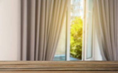 Odasında perdeler olan pencereye karşı boş ahşap masa