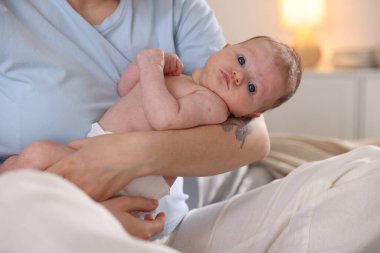 Anne yeni doğmuş bebeğini evde yatırıyor, yakın plan.