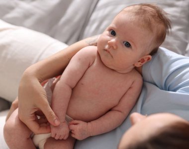 Anne, yeni doğmuş bebeğini evde uyuması için yatırıyor.