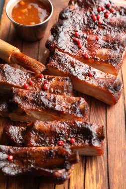 Lezzetli kaburgalar, sos ve fırça ahşap masada, yakın plan.
