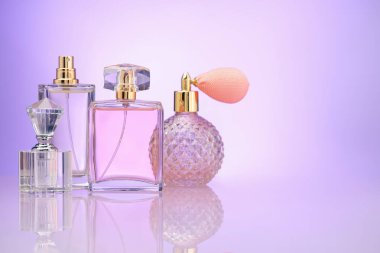 Ayna yüzeyindeki parfüm şişeleri menekşe gradyan arkaplan, metin için boşluk