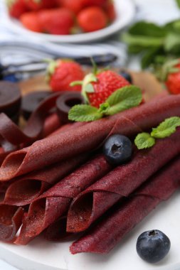 Lezzetli meyve dürümleri, çilekler, yaban mersini ve nane şekeri beyaz masada, yakın plan.