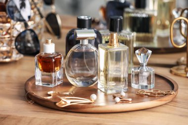 Farklı parfüm şişeleri ve aksesuarlar ahşap masada, yakın plan.