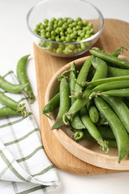 Taze taze bezelyeler beyaz ahşap masada, yakın plan.