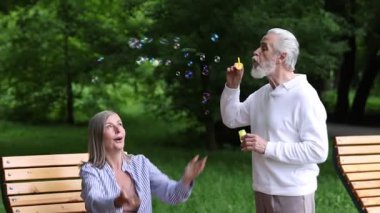 Güzel yaşlı çift parkta sabun köpüğüyle eğleniyor.