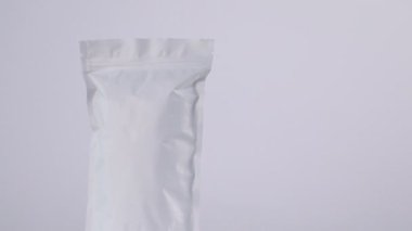 Açık gri arka planda dönen fermuar stand-up kesesi, yakın plan. Metin için boşluk