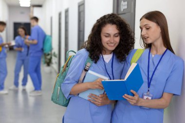 Üniformalı tıp öğrencileri kapalı alanda birlikte çalışıyor, seçici bir odak noktası var.