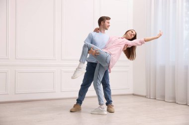 Mutlu çift evde beyaz duvarın yanında dans ediyor.