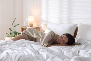 Evde yumuşak bir şilteyle yatakta yatan bir kadın. Metin için boşluk