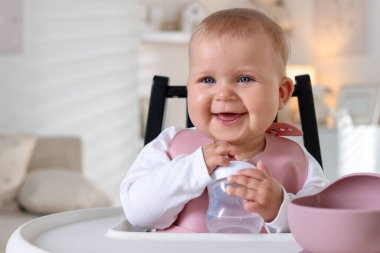 Evde şişe ile beslenme sandalyesinde sevimli küçük bebek