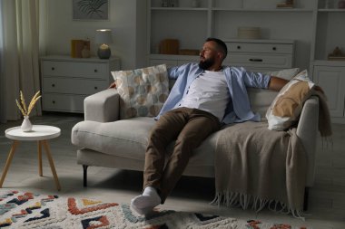 Uyum. Evdeki rahat koltukta dinlenen bir adam.