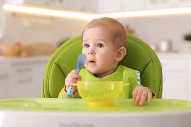 Küçük şirin bebek, yüksek sandalyede sağlıklı yiyecekler yiyor.