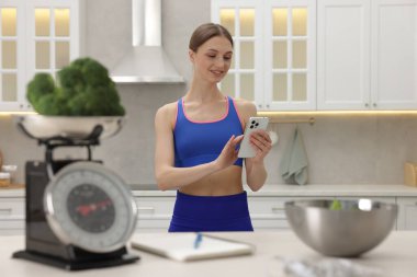 Mutfak terazisi, brokoli, defter, mezura, kapalı alanda salata ve mezura kullanan bir kadın.