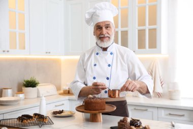 Yaşlı pasta şefi mutfaktaki tatlılarla birlikte masada.
