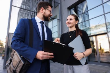 Mutlu iş arkadaşları ofis binasının yakınında düşük açılı bir şeyler tartışıyor.