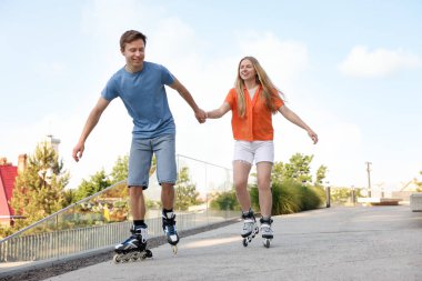 Mutlu çift sokakta birlikte paten kayıyor.