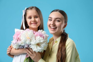 Anne ve kızı açık mavi arka planda bir buket güzel şakayıkla
