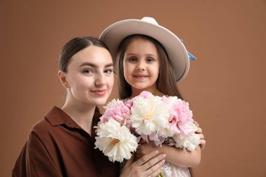 Anne ve kızı kahverengi arka planda bir buket güzel şakayıkla