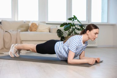 Sportif kadın evde kalas egzersizi yapıyor.