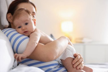 Anne yeni doğmuş bebeğini evde uyutuyor.