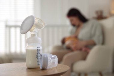 Sütlü meme pompası. Anne bebeğini evde emziriyor, seçici bir şekilde.