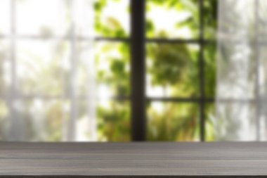 Odasında perdeler olan pencereye karşı boş ahşap masa