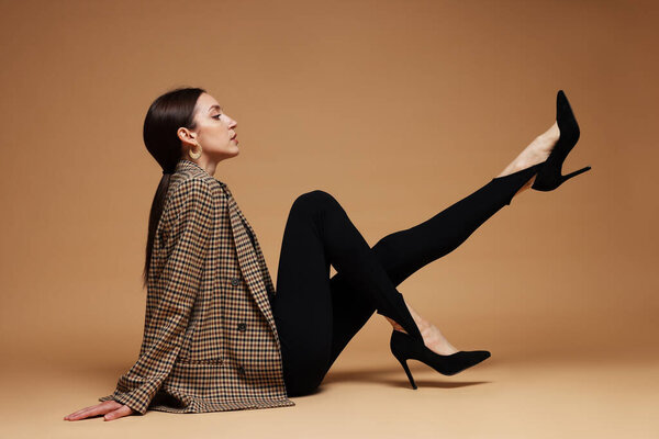 Полнометражный портрет красивой женщины в стильном наряде на бежевом фоне