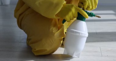 Koruyucu kıyafetli hamamböceklerine böcek ilacı sıkan hamam böceği kontrol görevlisi.