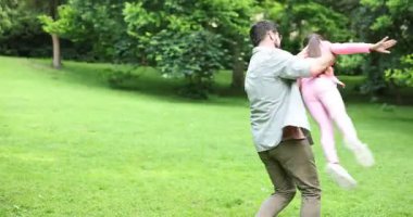 Aile kaçamağı. Mutlu ebeveynler parkta kızlarıyla eğleniyor.