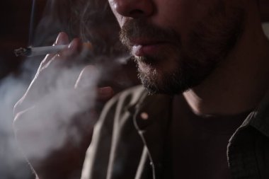 Arka planda sigara içen adam, yakın plan.