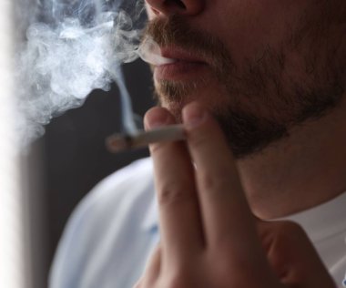 Arka planda sigara içen adam, yakın plan.