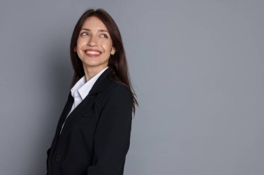 Gri arka planda takım elbiseli mutlu kadın, mesaj için boşluk