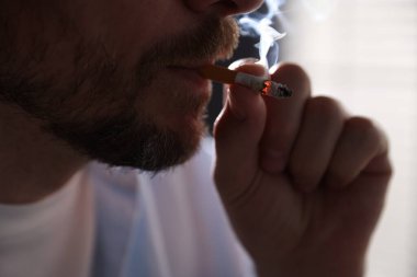 Arka planda sigara içen adam, yakın plan.