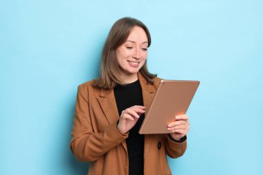 Açık mavi arka planda modern tabletli kadın