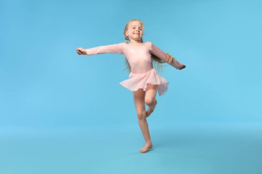 Açık mavi arka planda dans eden tatlı küçük kız.