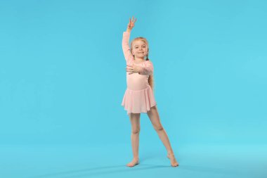 Açık mavi arka planda dans eden tatlı küçük kız.